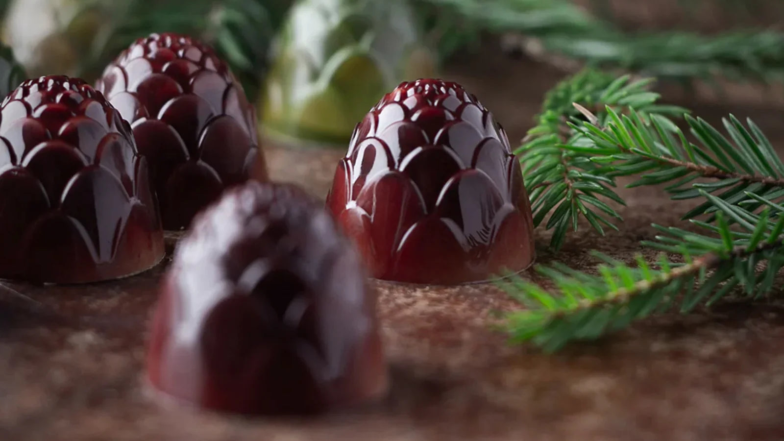 Three pine cone chocolates made with CW12124 mould displayed on wood with pine branches